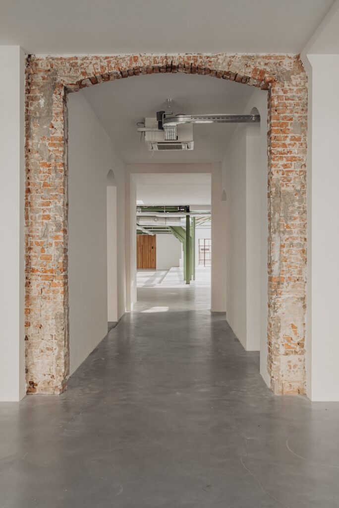 Doorkijk door een moderne gang met zichtbaar oud metselwerk in een gerenoveerd pand aan de Plantage Middenlaan.